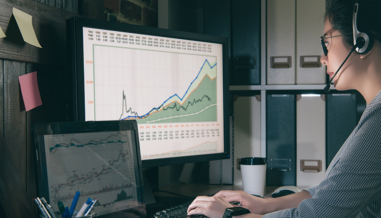 woman working at home with charts on monitors